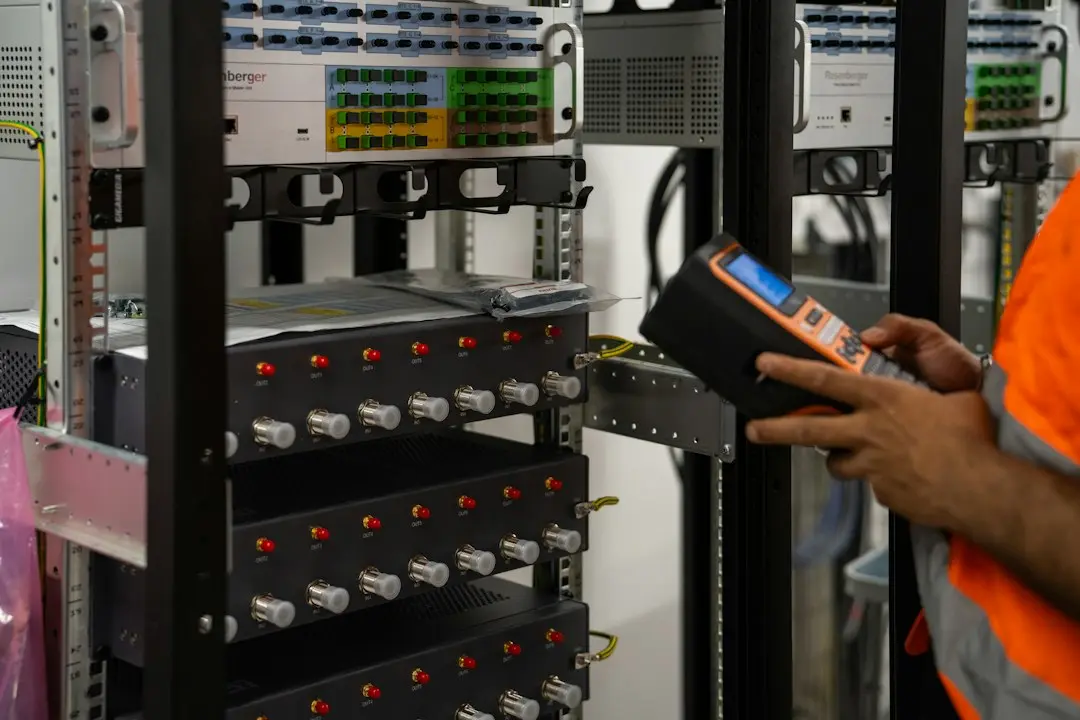 Technician testing a rack of network equipment with a handheld meter